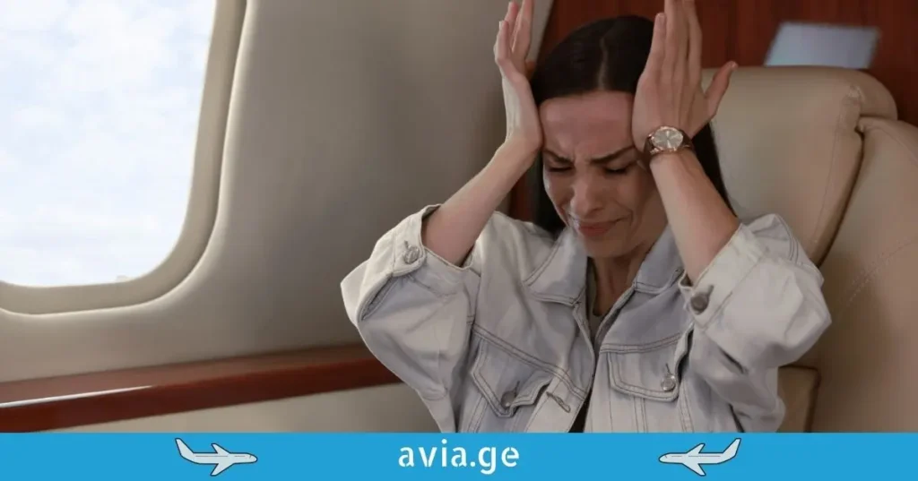 A woman experiencing a panic attack or anxiety due to aerophobia while sitting in an airplane seat next to a window.