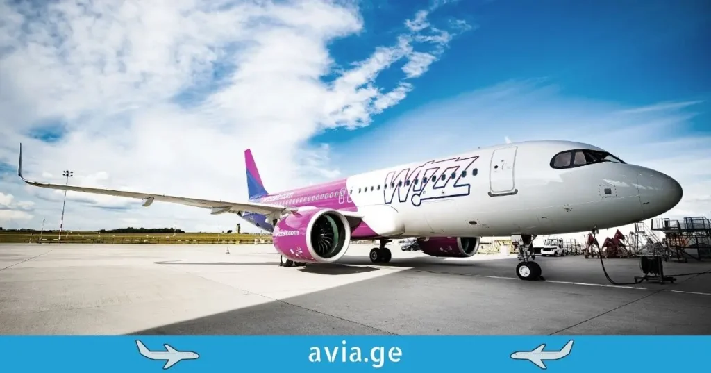 Wizz Air Airbus aircraft parked on the airport tarmac under a blue sky with the avia.ge logo at the bottom.