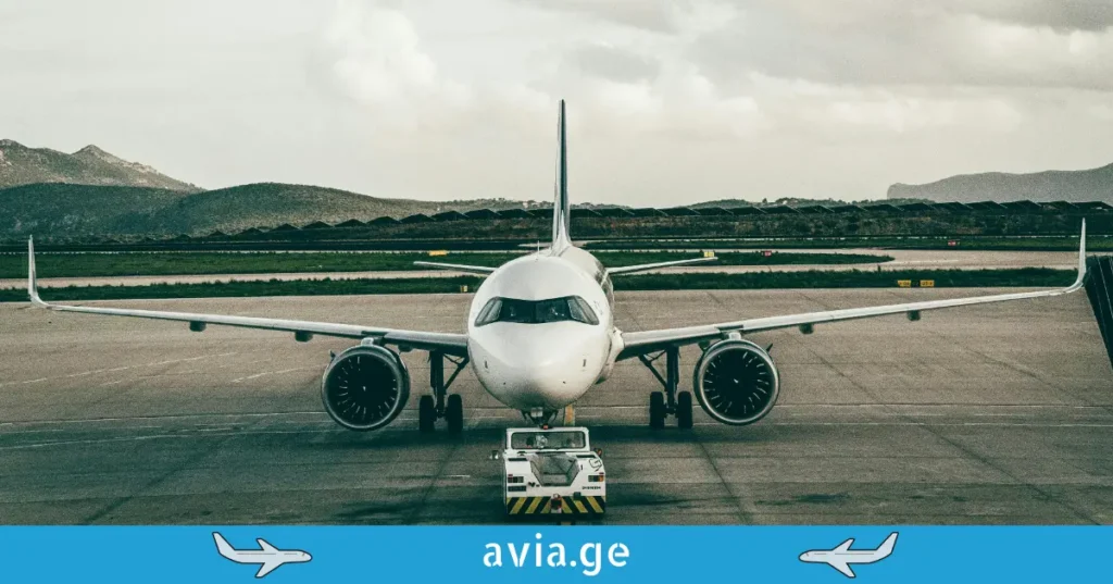 Front view of a commercial airplane on the tarmac with mountains in the background.