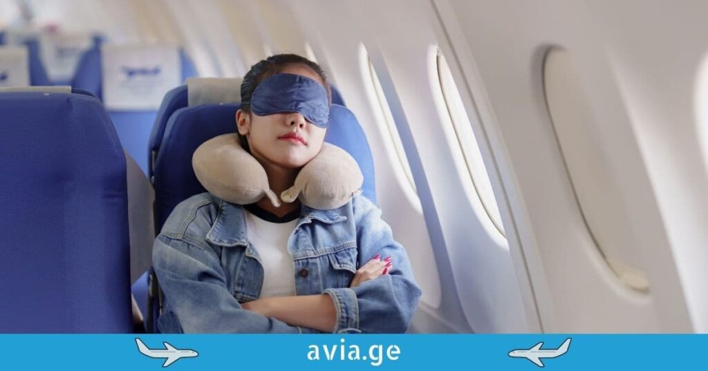 A female passenger sleeping comfortably on a plane using a neck pillow and eye mask.