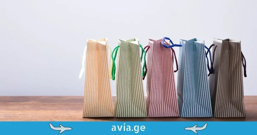 Row of colorful striped shopping bags on a wooden surface with avia.ge travel branding