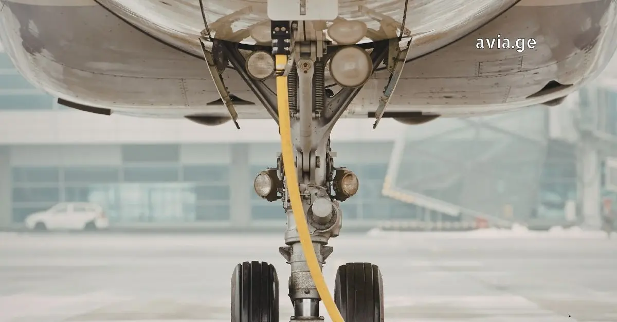 Airplane nose landing gear detailed view with ground power cable attached.