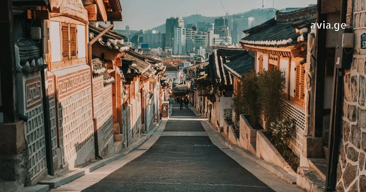 Steep street in Bukchon Hanok Village, Seoul, with traditional Korean houses (hanoks) looking towards the modern city skyline