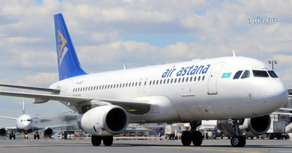 Air Astana Airbus A321neo taking off with landing gear still extended over sun-kissed mountains.