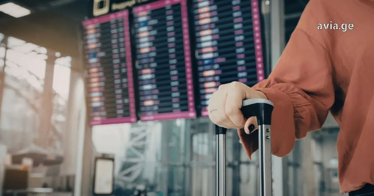 Passenger with suitcase watching airport flight status board