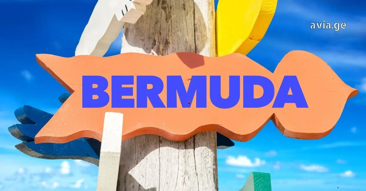 A colorful wooden signpost with "BERMUDA" text against a clear blue sky and ocean background.