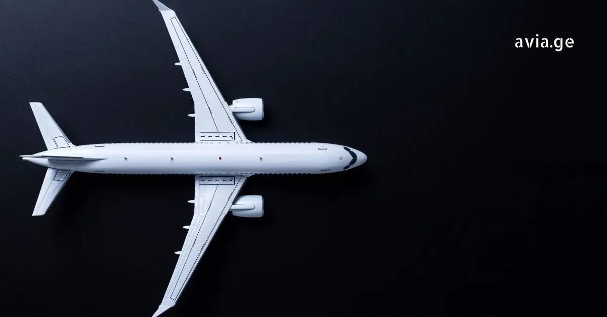Top-down view of a white model airplane on a black background.