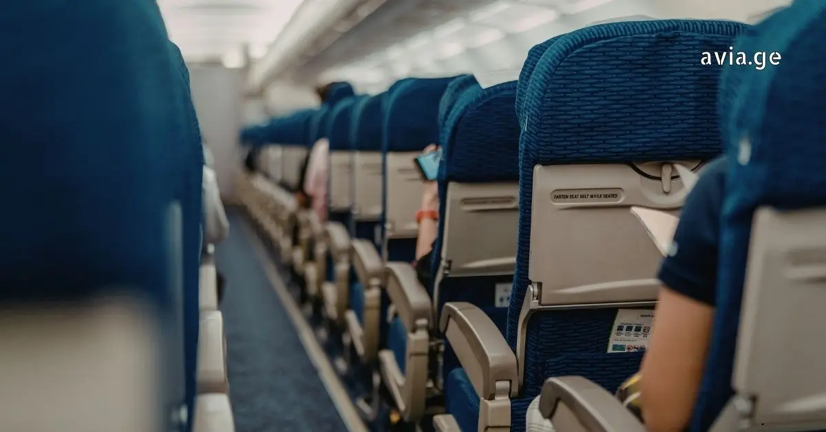 Rear view of economy class airplane cabin aisle with passengers seated