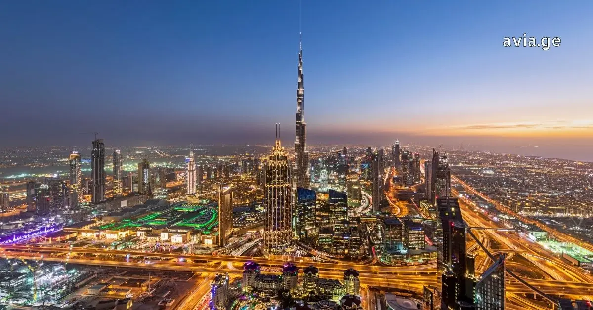 Aerial view of the Burj Khalifa and the Dubai skyline at sunset with city lights and highway traffic