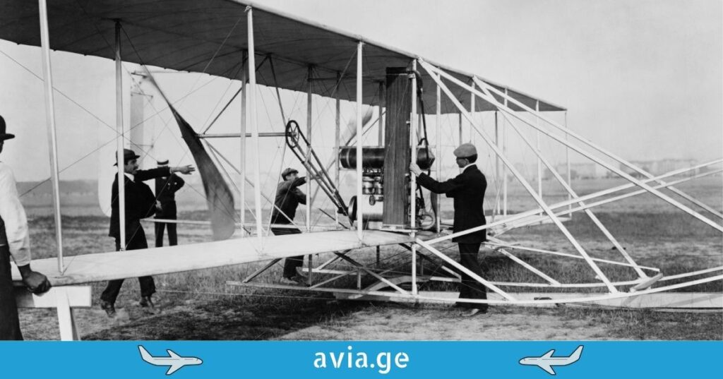 A group of people around a vintage biplane on a grassy field.