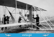 თვითმფრინავის შექმნის დაუჯერებელი ისტორია: ადამიანი, რომელმაც ცა დაიპყრო A group of people around a vintage biplane on a grassy field.