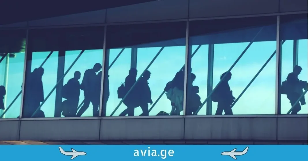 Georgia Airport Passenger Traffic 2025 Silhouettes of passengers walking through an airport terminal bridge with avia.ge logo.