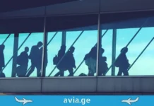 2025 წელი საქართველოს ავიაციაში: რეკორდული მაჩვენებლები და მზარდი დინამიკა Silhouettes of passengers walking through an airport terminal bridge with avia.ge logo.