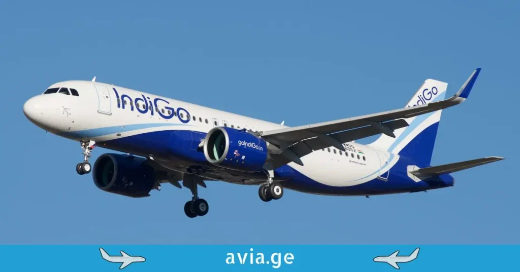 Close-up of an IndiGo Airlines plane taxiing at an airport, with another plane (Emirates) tail fin visible behind it.