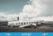 როგორ გადავრჩეთ, თუ თვითმფრინავი ჩამოვარდა: რეალური შანსები და გადარჩენის ინსტრუქცია Wreckage of a DC-3 airplane on a volcanic beach in Iceland, with two people posing on it.