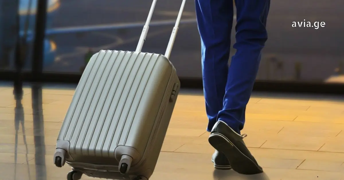 მგზავრი აეროპორტში ვერცხლისფერი ჩემოდნით