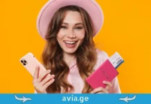 როგორ შევიძინოთ იაფი ავიაბილეთები ონლაინ? მომღიმარი ქალი პასპორტით და სმარტფონით
