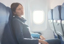 რომელია საუკეთესო ტურისტული სააგენტოები საქართველოში? ქალი მგზავრი თვითმფრინავის სავარძელში სძინავს, Avia.ge-ს ლოგო ზედა კუთხეში