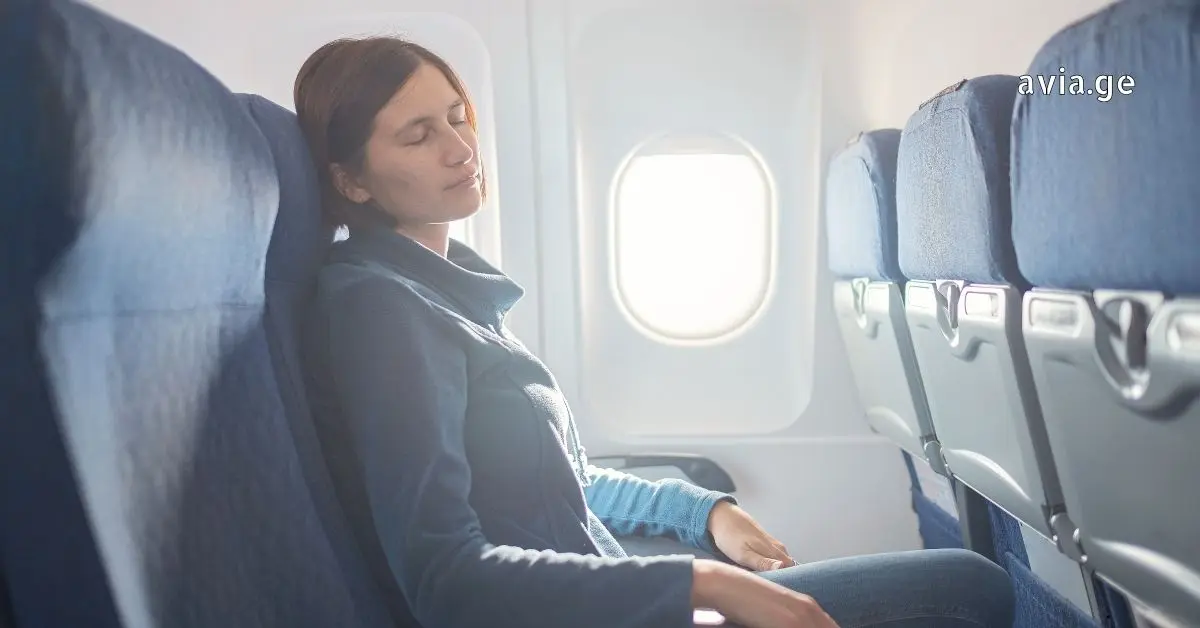 ქალი მგზავრი თვითმფრინავის სავარძელში სძინავს, Avia.ge-ს ლოგო ზედა კუთხეში
