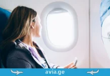 როგორ იმოგზაურა ქალმა მსოფლიოს გარშემო ავიაბილეთების გარეშე? გოგონა თვითმფრინავში ილუმინატორთან, რომელიც ავიაბილეთების გარეშე მოგზაურობაზე ფიქრობს.