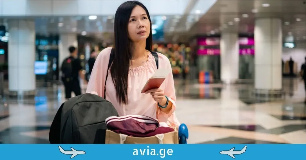 ქალი ბარგით აეროპორტის ტერმინალში.