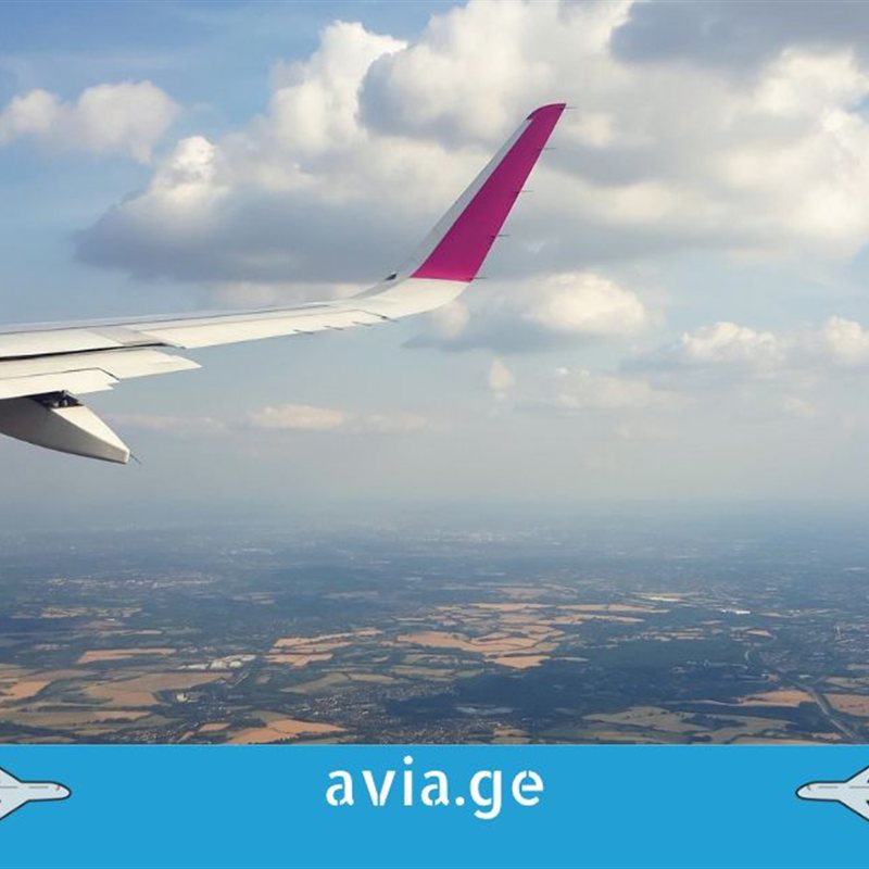 Wizz Air-ის თვითმფრინავის ფრთა ღრუბლებისა და ხმელეთის ფონზე
